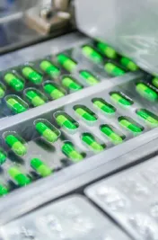 Green medicine capsules on blistering conveyor belt